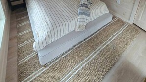 Een knus kamertje met een bed, een nachtkastje en een raam.