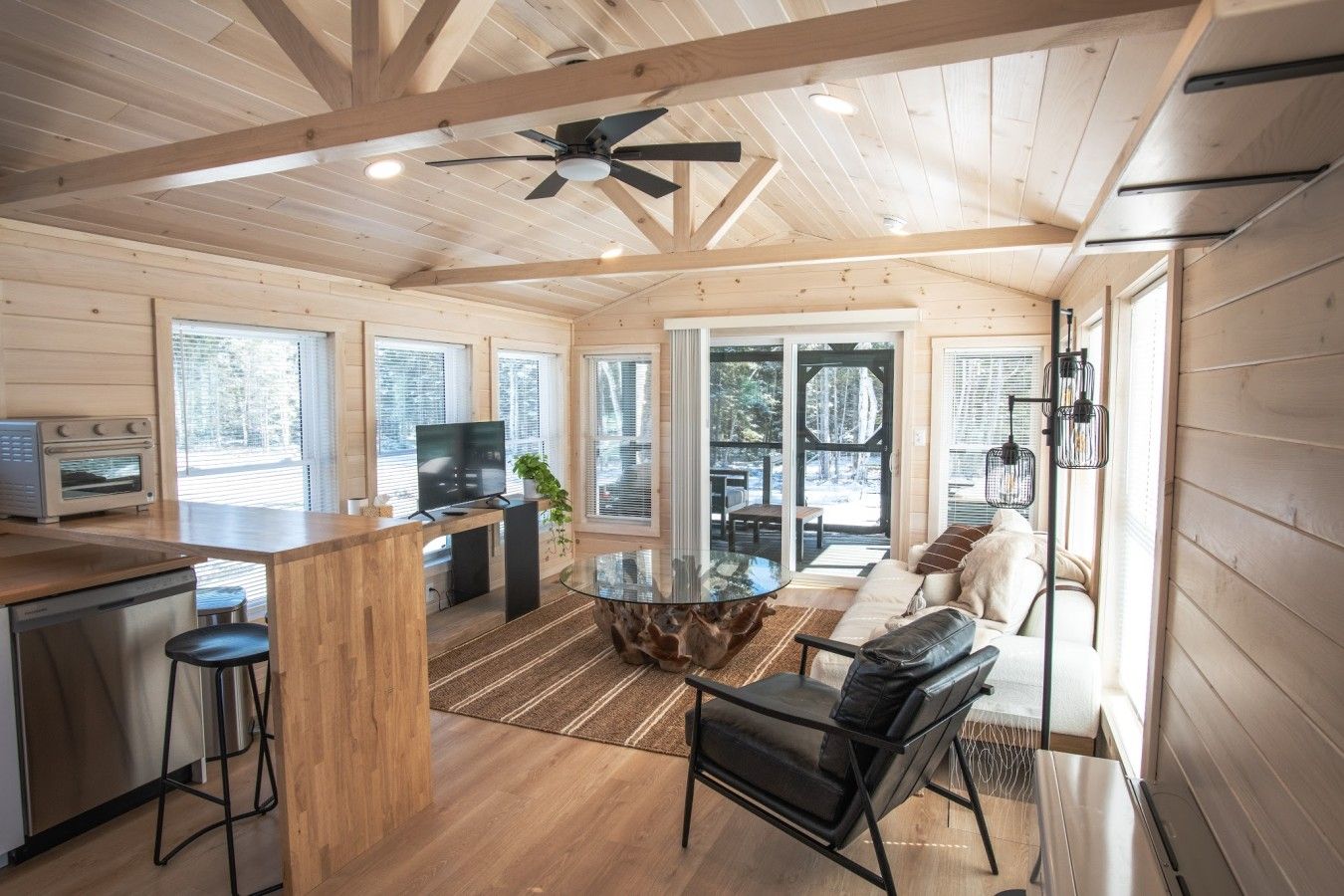 Una habitación amplia con techo de madera, televisor, mesa de comedor y sofá.