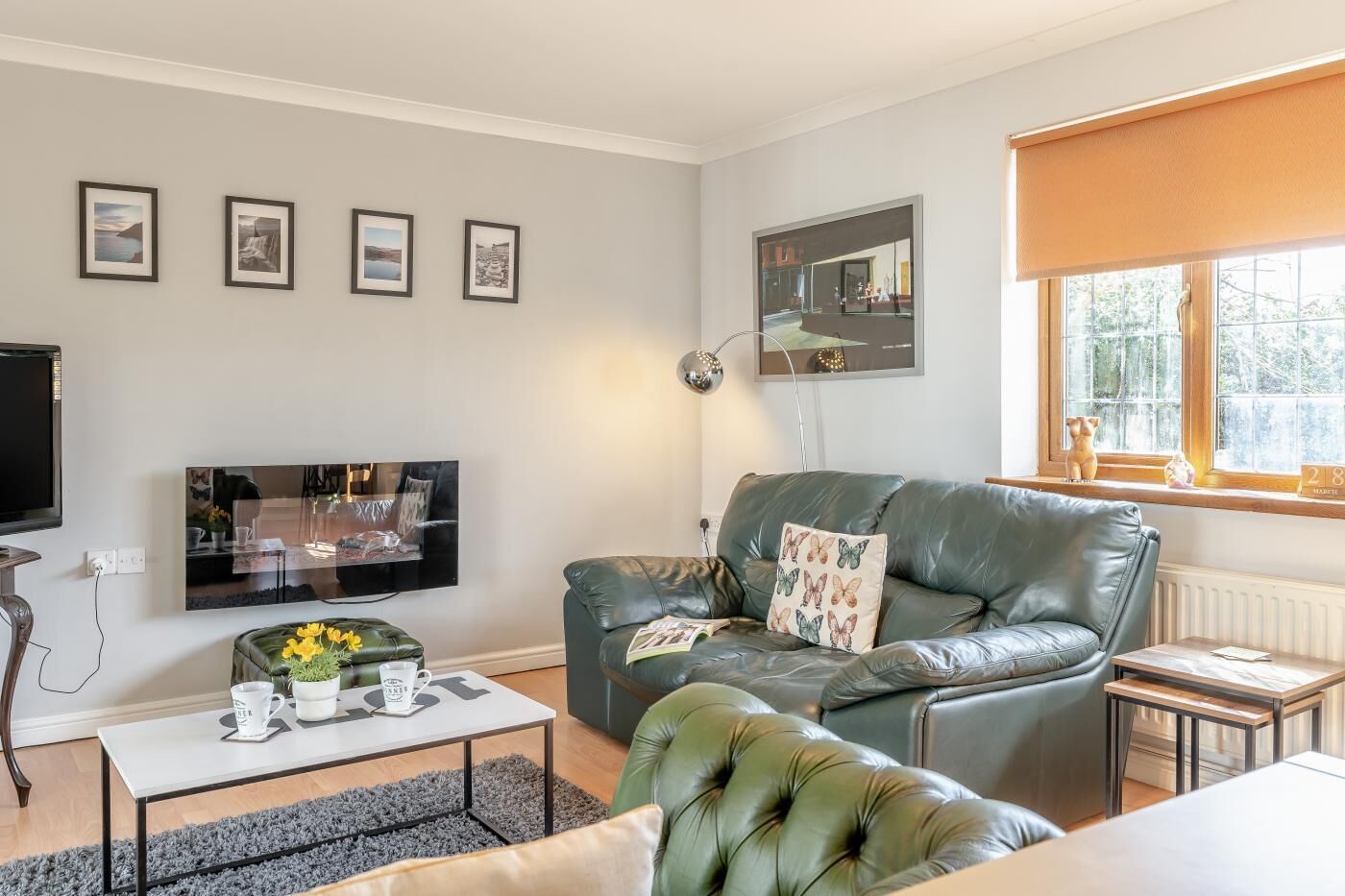 A living room with a sofa, a coffee table, a TV, and framed pictures on the wall.