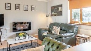 Ein Wohnzimmer mit einer Couch, einem Couchtisch, einem Fernseher und gerahmten Bildern an der Wand.