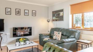 A living room with a sofa, a coffee table, a TV, and framed pictures on the wall.