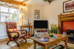 Una sala de estar acogedora con un sillón de cuero, una mesa de centro de madera, un televisor de pantalla plana y una chimenea.