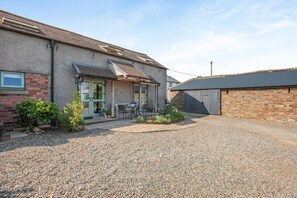 A residential property with a gravel driveway, a patio with outdoor seating, and a garage.