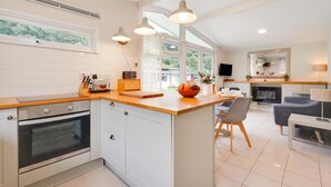 Una cucina moderna con mobili bianchi, un piano di lavoro in legno e un'ampia finestra che offre luce naturale.