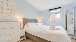 Una camera da letto moderna con un letto, comodini, un'opera d'arte incorniciata e una finestra con persiane.