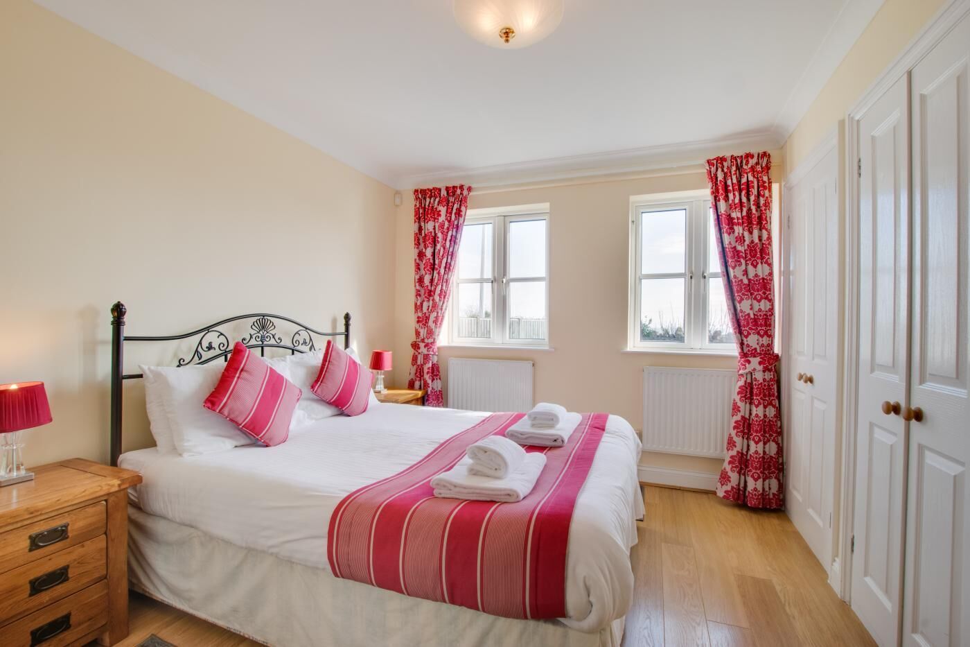 Een slaapkamer met een bed, nachtkastjes, een raam en een deur.