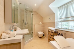 A modern bathroom with a glass shower enclosure, a white sink, and a toilet. There is a window with blinds and a basket of towels. - 3 Bed in Salwayash (oc-g31888) (Salwayash)