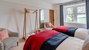 A hotel room with two beds, a wooden wardrobe, a chair, and a window with a view of the outdoors. - 2 Bed in Alyth (oc-e31854) (Auchrannie)