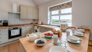 A modern kitchen with a built-in oven, a washing machine, and a large window offering a view of the countryside. - 2 Bed in Alyth (oc-e31854) (Auchrannie)