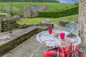 A stone wall, a metal table with a newspaper, a bowl, and a chair. - 1 Bed in Longnor (oc-y32018) (Heathylee)