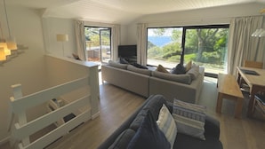 Un salon moderne avec un canapé, un téléviseur et une vue sur l’extérieur.