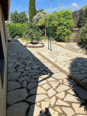 Un sentier pavé de pierres mène à un bâtiment doté d’une structure métallique verte.