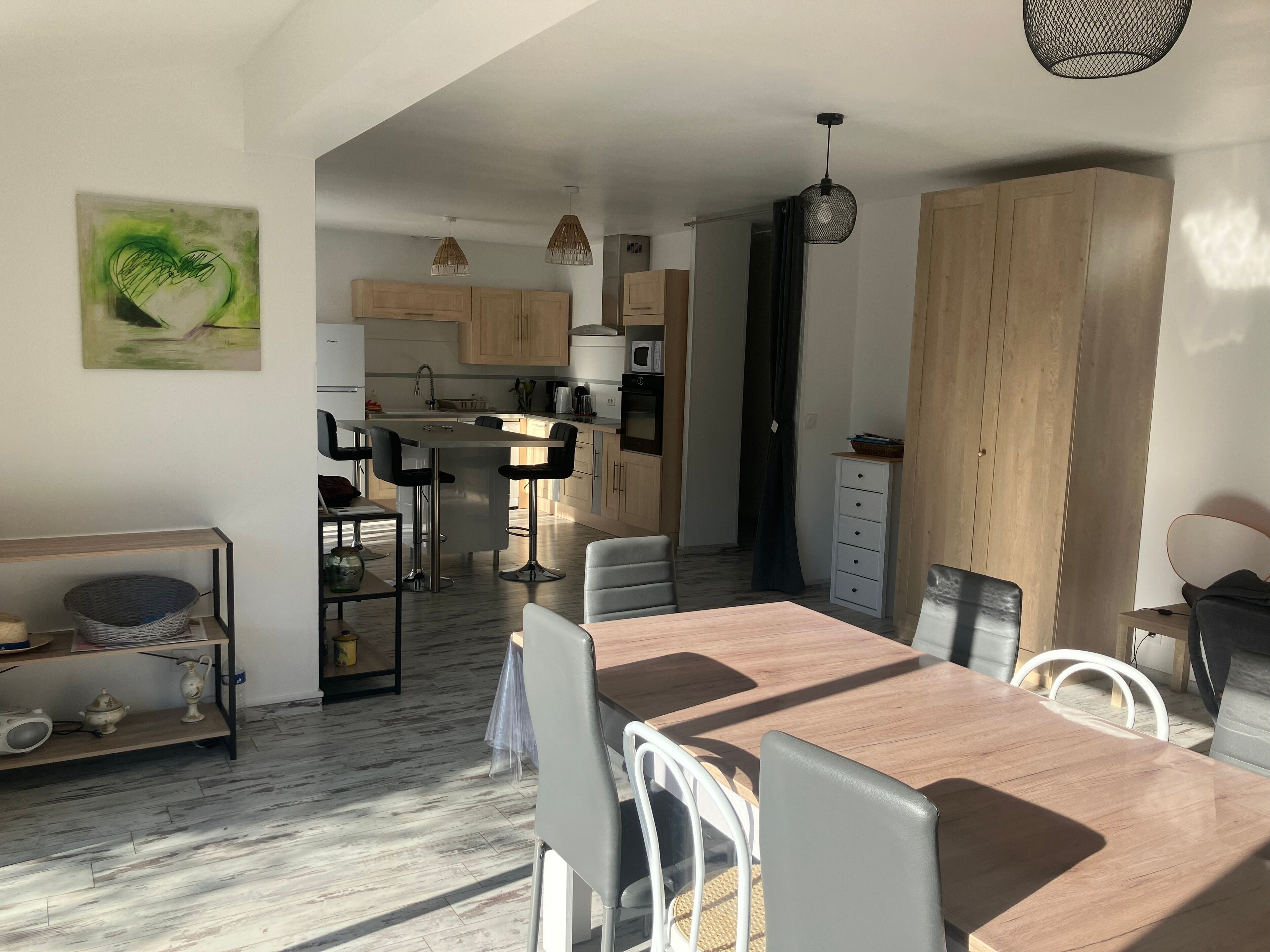 Une cuisine moderne avec des meubles en bois, un îlot central et des luminaires suspendus.