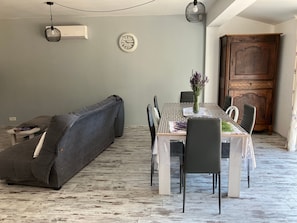 Un coin repas avec une table dressée pour quatre personnes, un canapé gris et un meuble en bois.