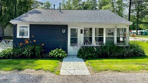 A single-story house with a dark blue exterior, a front porch, and a garage. - Endless Summer Cottage - walk to the GOTL strip (Geneva)
