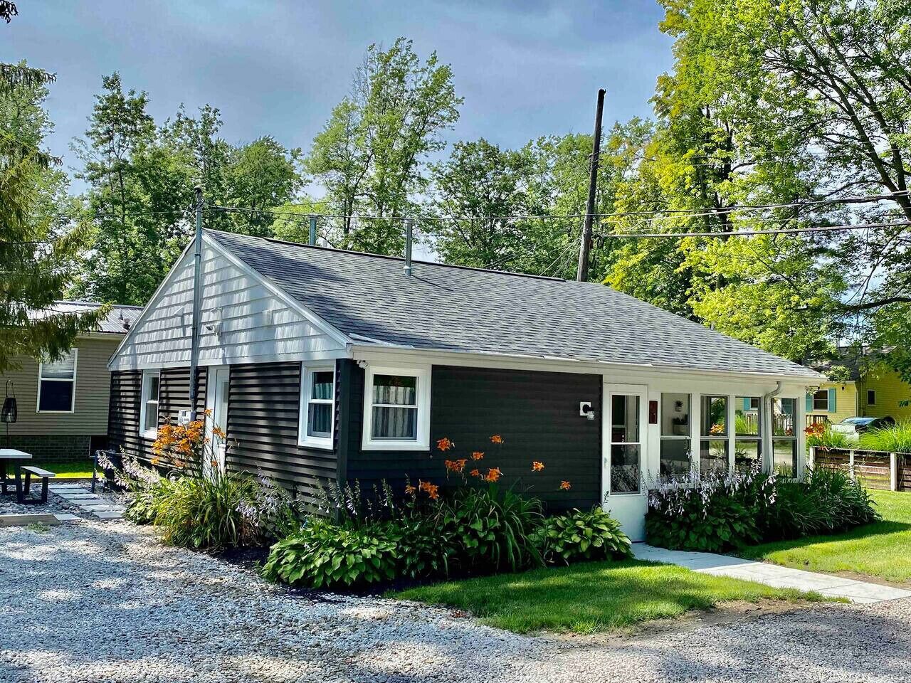A single-story house with a dark exterior, a sloped roof, and a covered porch.