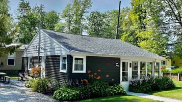 A single-story house with a dark exterior, a sloped roof, and a covered porch.