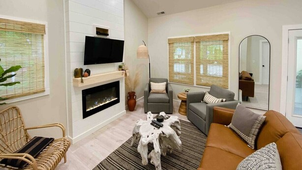 A modern living room with a fireplace, comfortable seating, a flat-screen TV, and large windows. - Endless Summer Cottage - walk to the GOTL strip (Geneva)