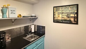A kitchen with a black countertop, a sink, and a blue cabinet. There is a framed picture of a motel on the wall. - Modern Retro #10, WiFi, A/C, walk to the Strip (Geneva)