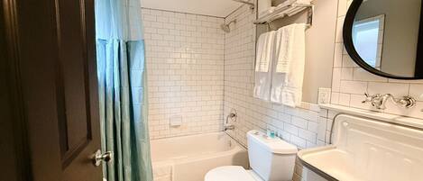 Une salle de bain avec une baignoire, des toilettes, un lavabo et un miroir.