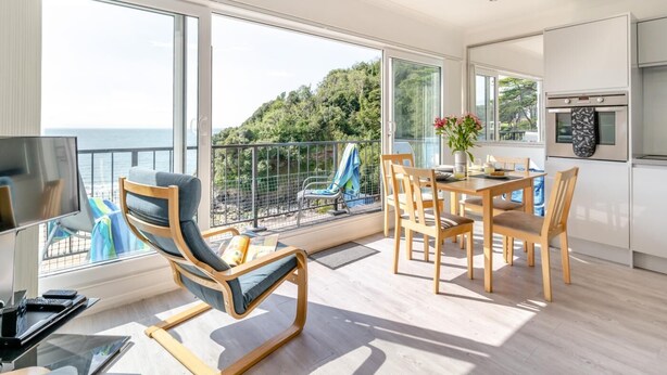 Ein moderner Raum mit Balkon, Essbereich und Küche.