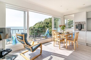 Ein moderner Raum mit Balkon, Essbereich und Küche.