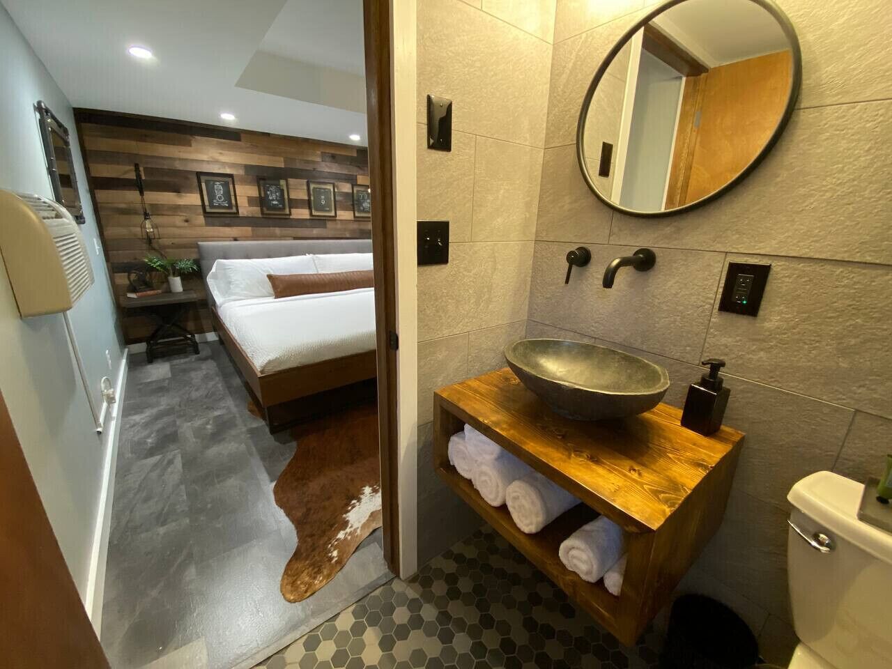 A modern bathroom with a wooden vanity, a large mirror, and a round sink.