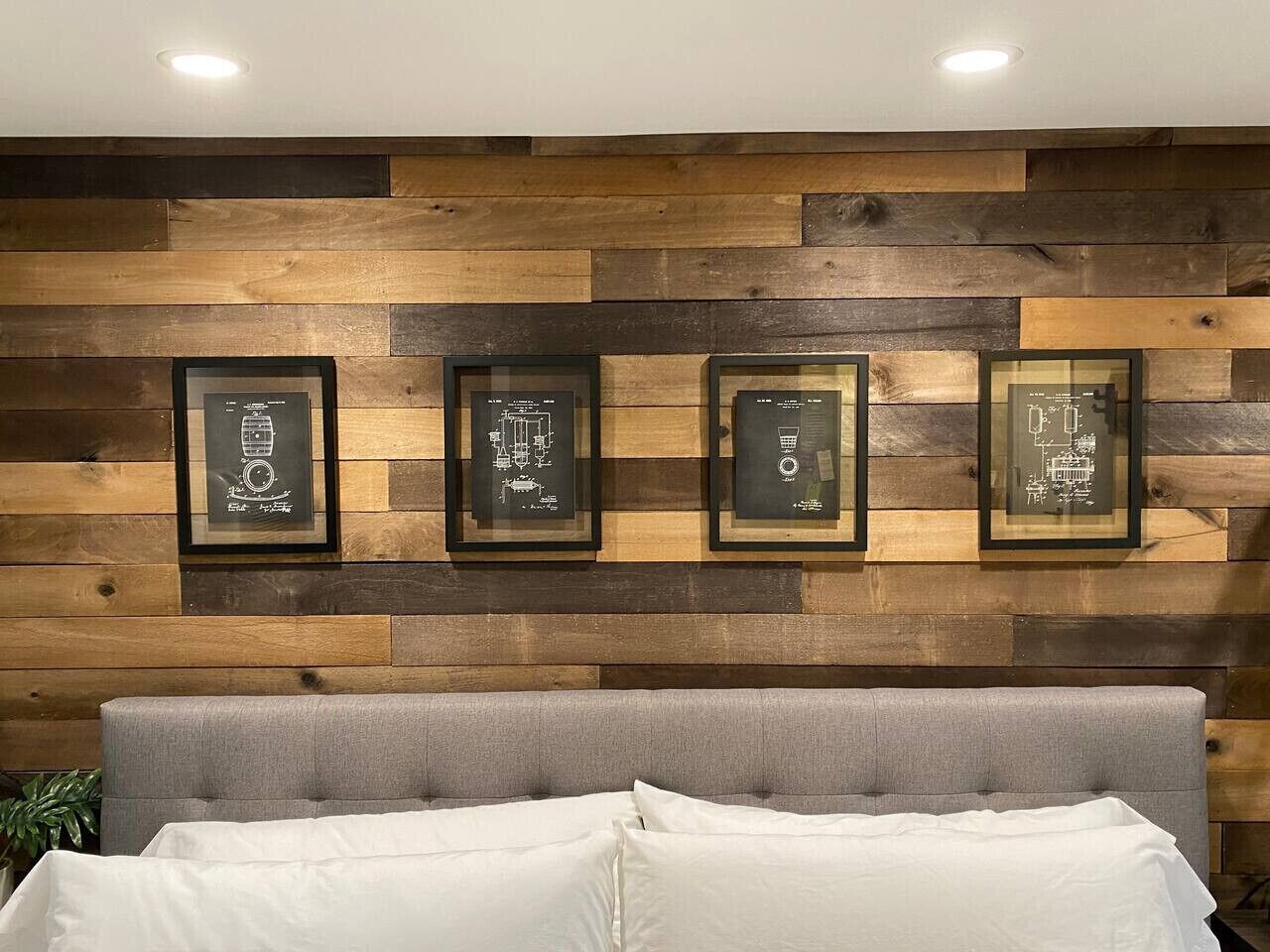 A bedroom with a wooden wall panel and four framed items.