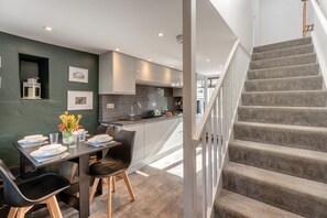A modern kitchen with grey cabinets, a dining area with a table set for four, and a staircase leading to an upper level. - 2 Bed in Dean (oc-h32066) (Dean)