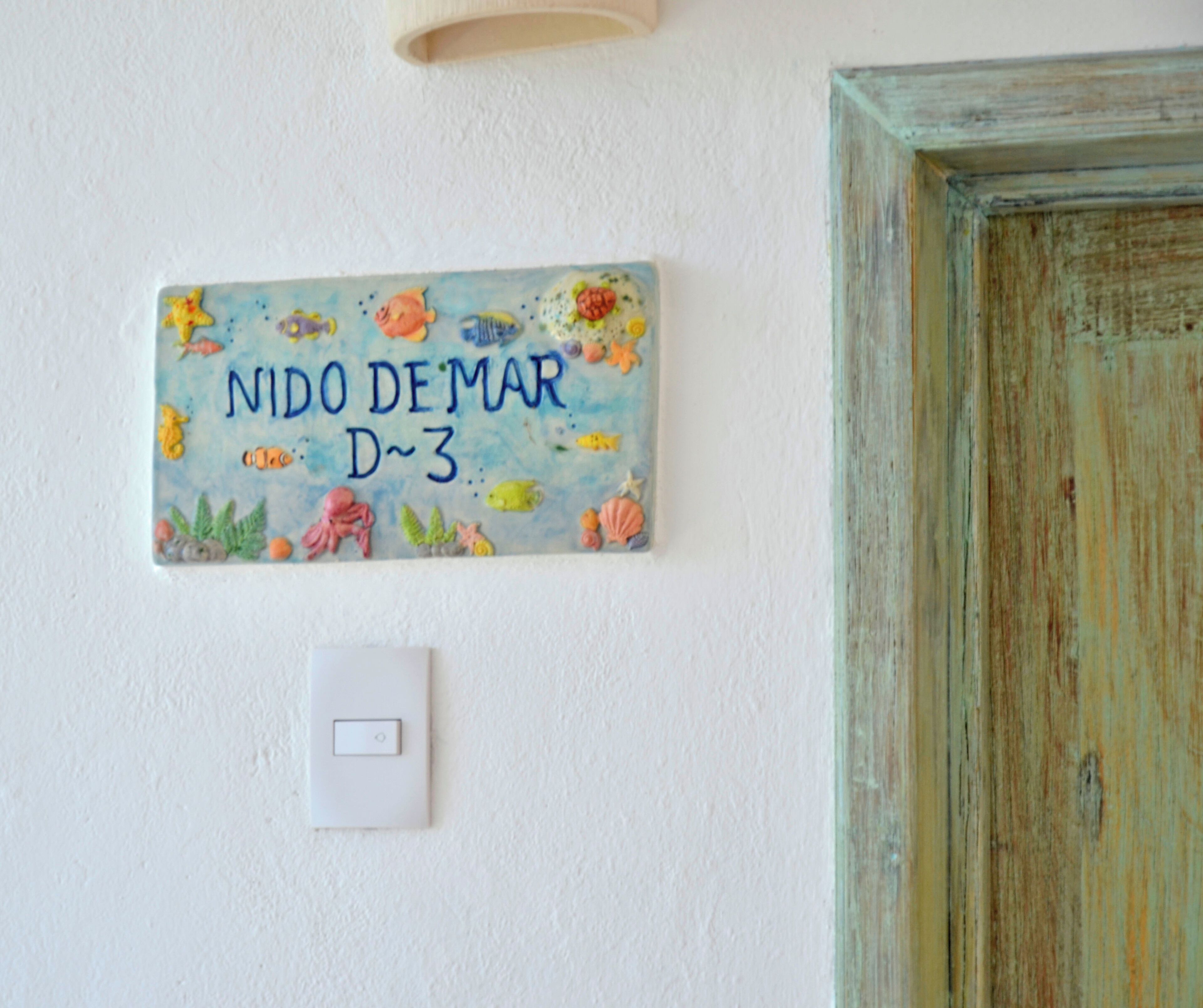 Un letrero en la pared con temática marina, un interruptor de luz y un marco de puerta rústico.