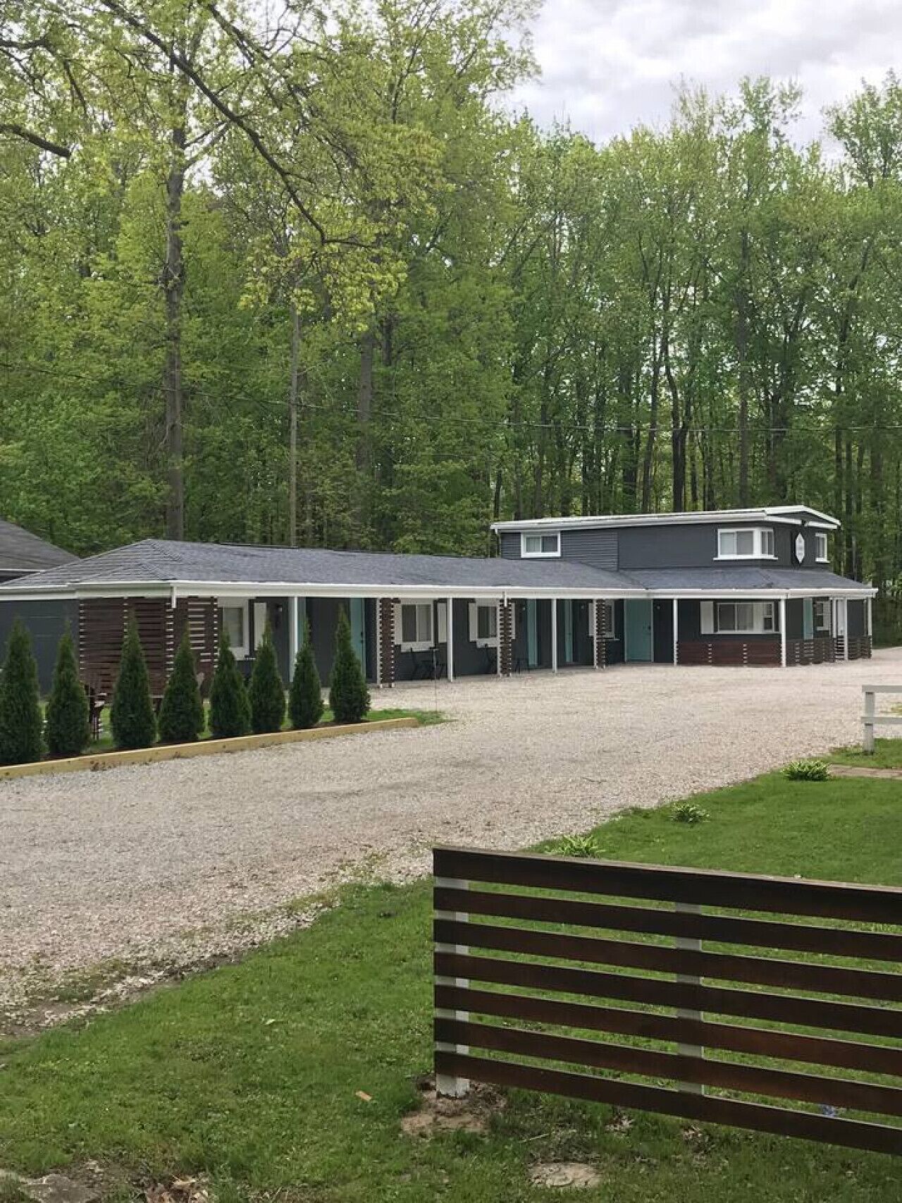 A row of cabins with a gravel driveway and a grassy area in front.