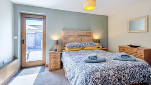 Een slaapkamer met een bed, nachtkastjes, een lamp, een spiegel en een deur die naar een balkon leidt.