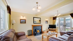 A cozy living room with leather sofas, a fireplace, a television, and a dining table. - 3 Bed in Gower (oc-hh23) (Port Eynon)