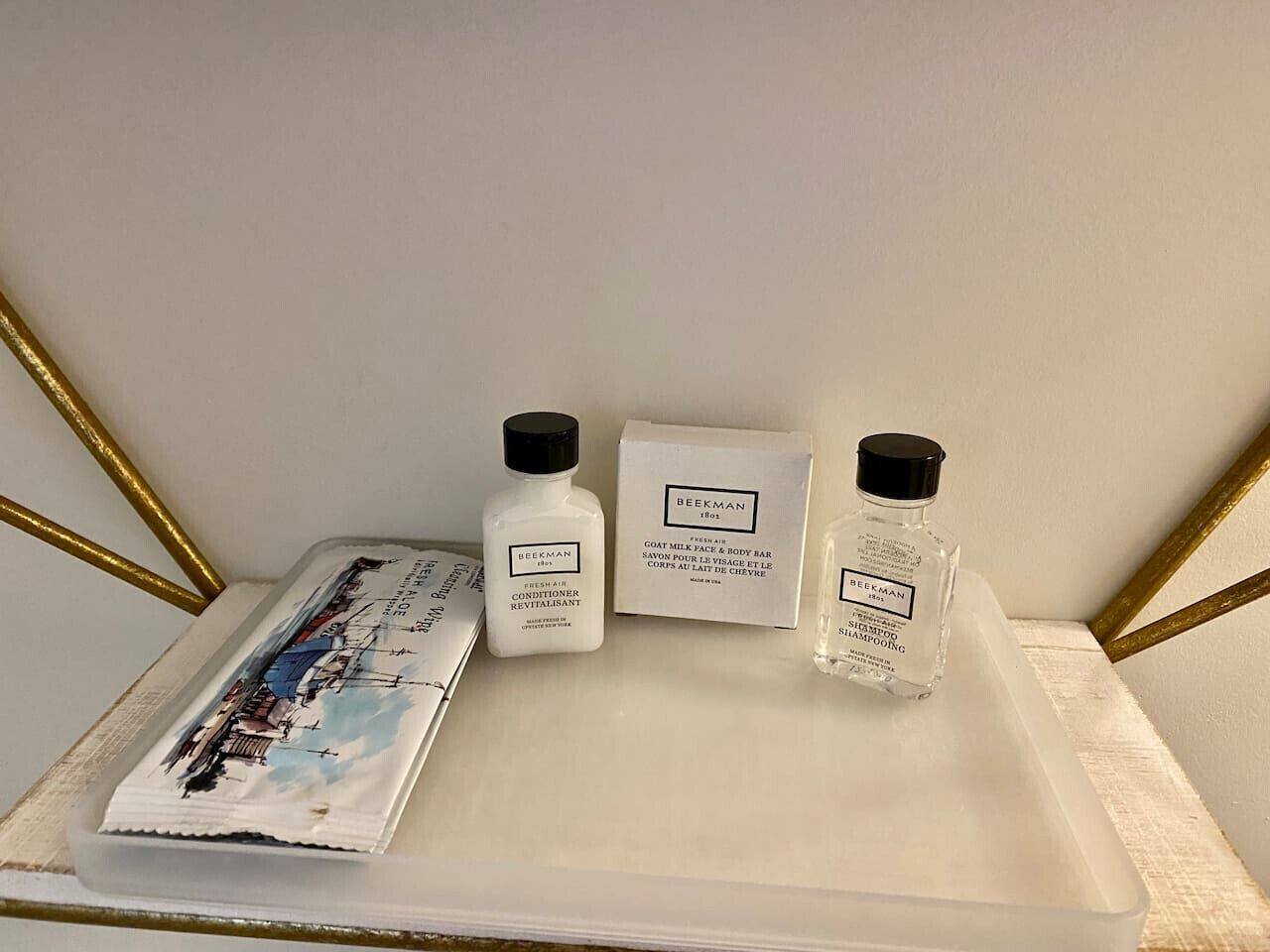 A tray with three skincare products and a magazine on a white surface with gold decorative elements.