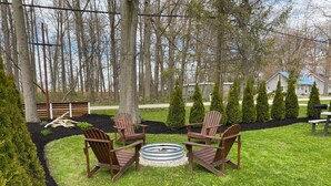 A backyard with a fire pit, four wooden Adirondack chairs, and a well-maintained lawn. - King Glamour #8, Walk to the Strip, A/C, WiFi (Geneva)