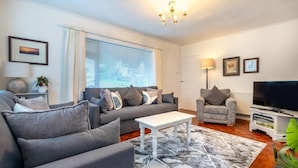 A modern living room with a grey sofa set, a white coffee table, and a TV stand with a flat-screen TV. - 4 Bed in Swansea (oc-hh642) (Mayals)
