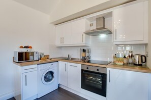 Een microgolfoven, een oven, een vaatwasser, kookgerei, borden en bestek