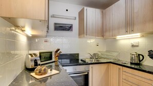 Eine moderne Küche mit Holzausstattung, einer Mikrowelle, einem Backofen, einer Spüle und einer Arbeitsplatte mit einem Brot.