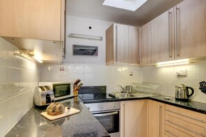 Eine moderne Küche mit Holzausstattung, einer Mikrowelle, einem Backofen, einer Spüle und einer Arbeitsplatte mit einem Brot.