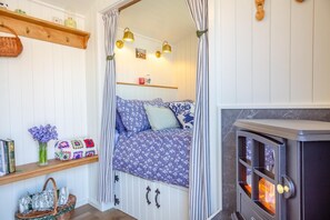 A cozy room with a bed, a fireplace, and a shelf with books and a basket. - 1 Bed in Llannefydd (oc-p32089) (Llannefydd)