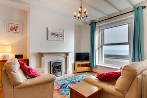 A living room with a fireplace, television, and a view of the sea. - 2 Bed in Mumbles (oc-hh382) (The Mumbles)