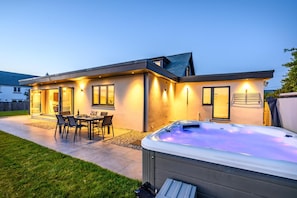 Ein modernes Haus mit Terrasse, Whirlpool und Essbereich.