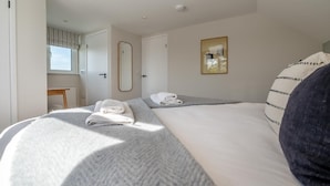 A hotel room with two beds, a window, a mirror, and a painting on the wall. - 4 Bed in St. Merryn (oc-f31095) (Saint Merryn)