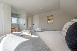 Ein Hotelzimmer mit zwei Betten, einem Fenster, einem Spiegel und einem Bild an der Wand.