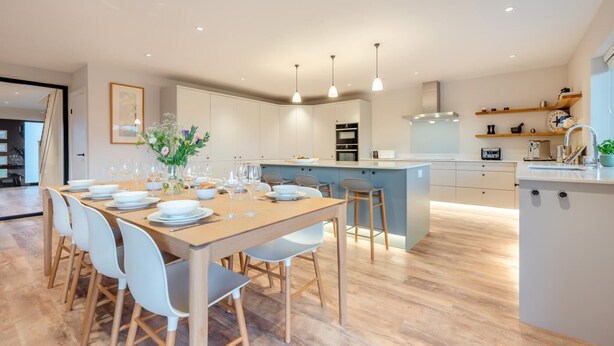 A modern kitchen with a central island, white cabinetry, and pendant lighting. - 4 Bed in St. Merryn (oc-f31095) (Saint Merryn)