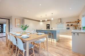 Una cocina moderna con una isla central, armarios blancos e iluminación colgante.