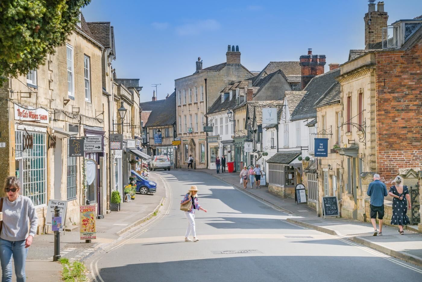 A street with buildings, shops, and pedestrians.