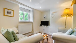 Ein gemütliches Wohnzimmer mit zwei Sofas, einem Couchtisch, einem Fernseher und einer Lampe.