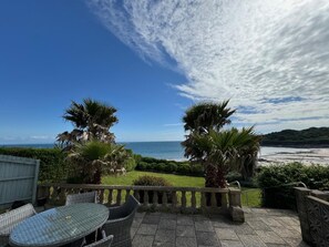 Eine Terrasse mit Tisch und Stühlen mit Blick auf einen Strand.