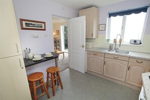 A compact kitchen with a countertop, stools, and a window. - 1 Bed in Langland (oc-hh147) (Newton)